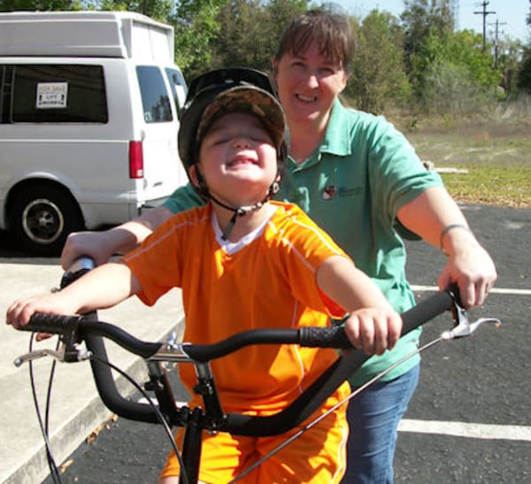 A Henderson Haven student riding a bike with a teacher