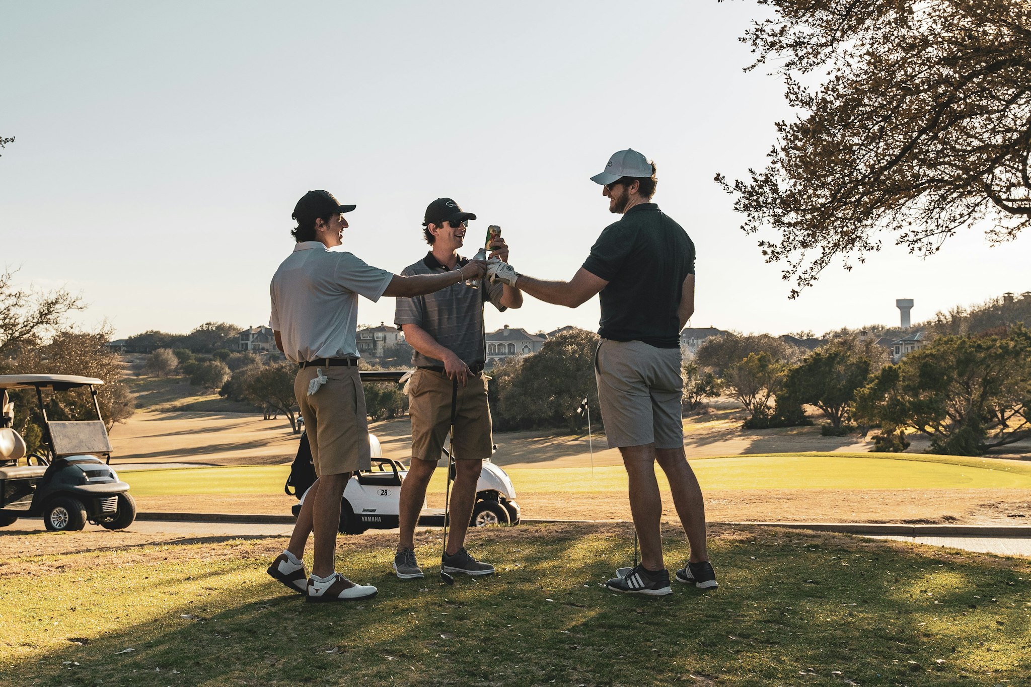Three golfers toasting with drinks on a sunny course